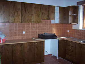 Kitchen area during construction stage. Dark wood doors and tiled splashback area.