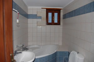 Bathroom, corner bath, WC and basin. Tiled throughout.