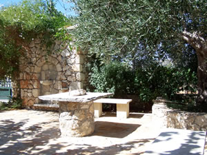 Stone built water feature, table and seating area under a shady tree