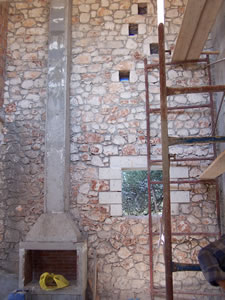 Exposed stonework surrounding fireplace, with small light windows fitted into the wall above the window